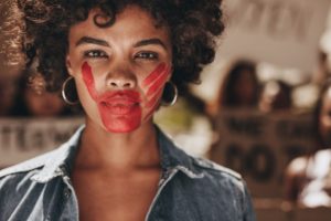 Foto de mujer con mano roja pintada en la cara