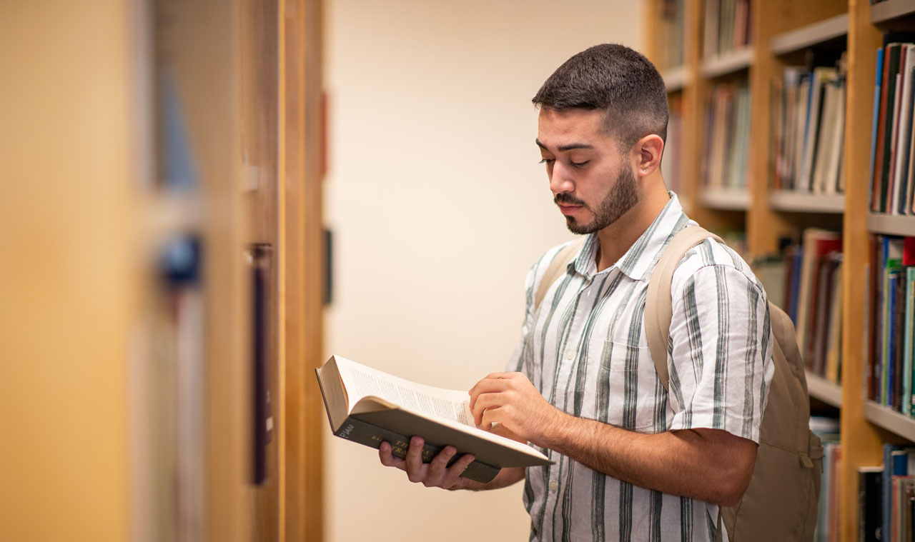 Estudiante RRP en biblioteca con libro