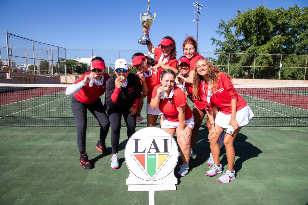 Equipo de tenis de campo femenino del Recinto de Río Piedras posa con las medallas de oro y la copa del campeonato