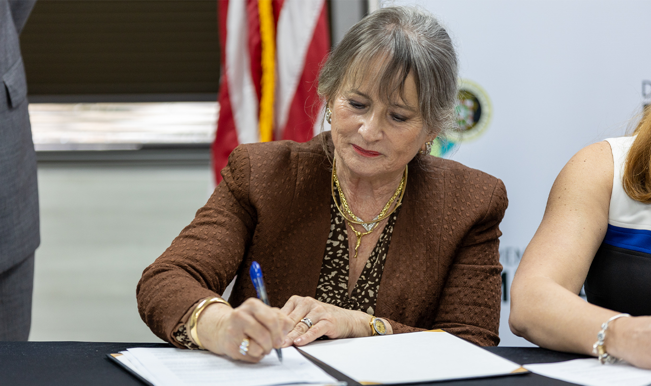 Foto de la rectora Angélica Varela Llavona firmando el memorando de entendimiento del departamento de la familia