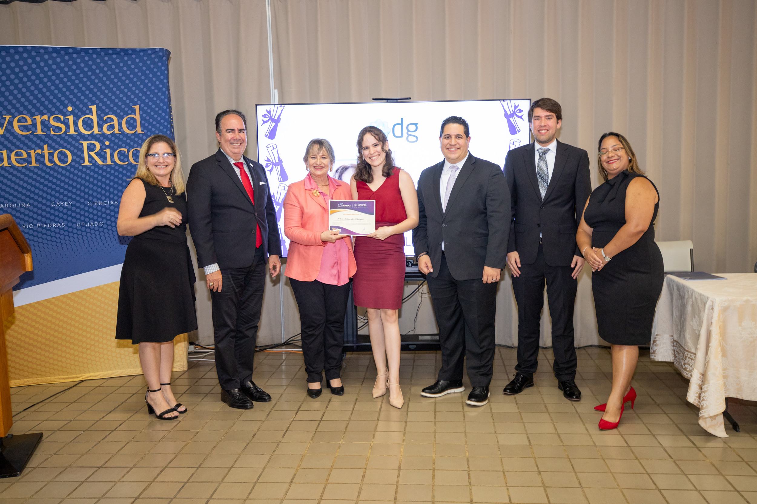 Valerie M. González Velázquez recibe la beca respaldada por IT Developers Group, junto a funcionarios de la UPR y representantes de UPRAA